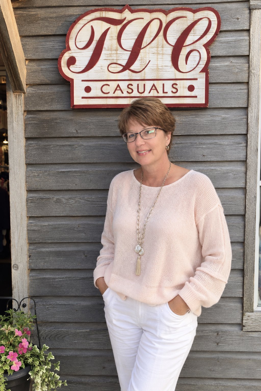 Tami Conard, founder of TLC Casuals, in front of the TLC Casuals sign